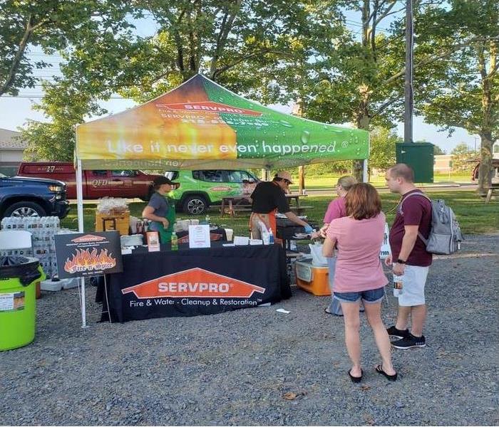 people standing in line in front of a SERVPRO tent and table